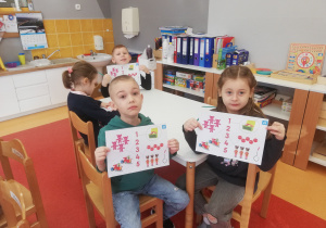 dzieci pokazują wykonane karty pracy